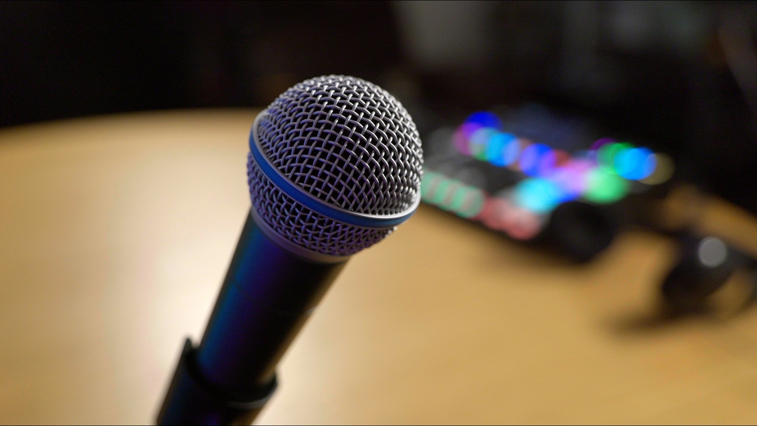 A dynamic microphone with the Little Empire Podcast Studio in soft focus in the background